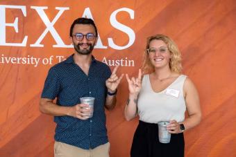 Two first-gen students pose in front of a burnt orange backdrop at a Horns Helping Horns event