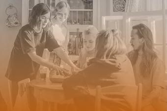 Five students work together at a kitchen table