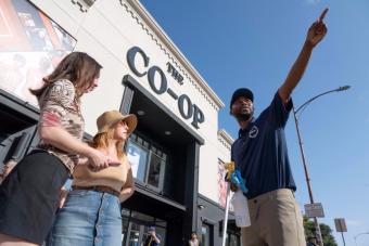 A student in a West Campus Ambassadors polo points two other students in the right direction